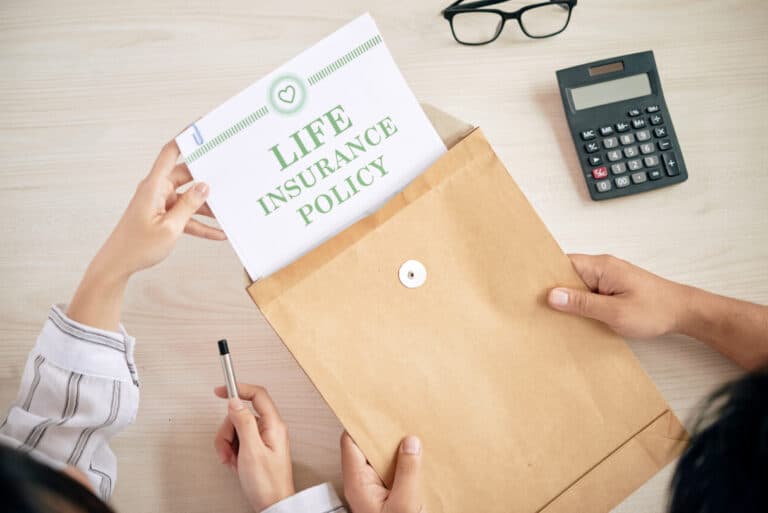 Life insurance policy document being taken from an envelope on a desk