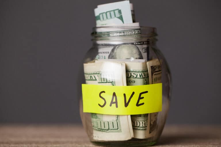 Glass jar of hundred-dollar bills labeled SAVE
