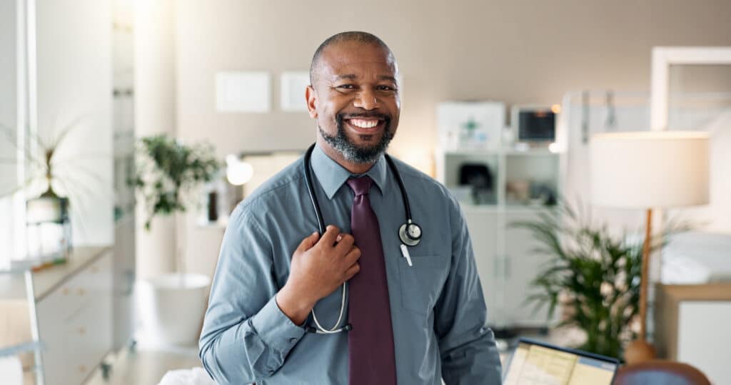 Smiling physician with a stethoscope standing in his medical office