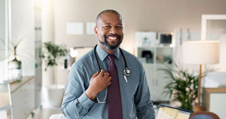 Smiling physician with a stethoscope standing in his medical office