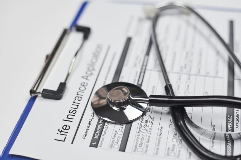 Stethoscope lying on a life insurance application on a clipboard