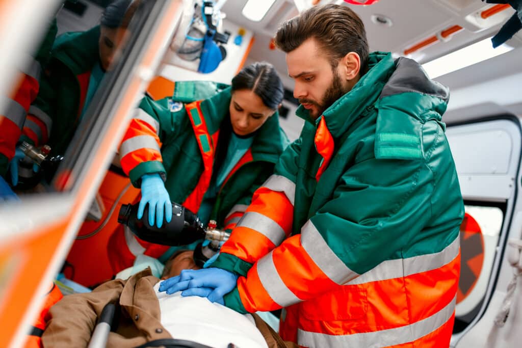 Paramedics treating a patient on a stretcher inside an ambulance