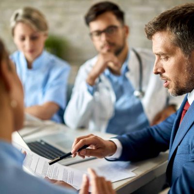 Mid adult businessman and healthcare workers analyzing documents during a meeting in the office.