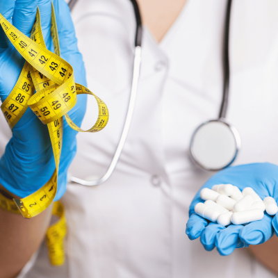 medical professional holding pills and measuring tape