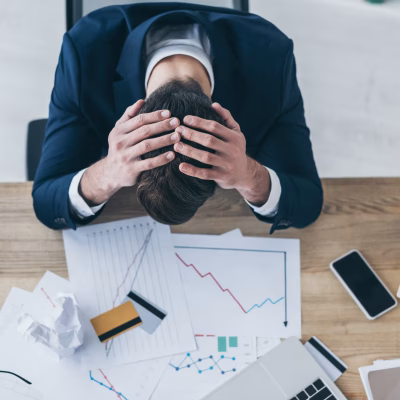 top view of depressed businessman holding hands on bowed head while sitting at desk with documents