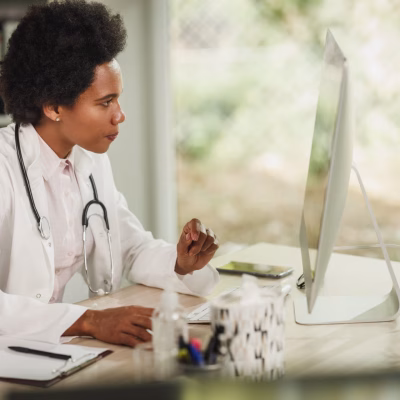 Shot of an African female doctor sitting alone and working on computer in her consulting room.